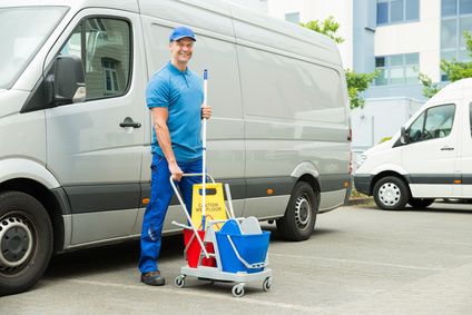 Happy Male Cleaner In Front Of Van With Cleaning Equipments