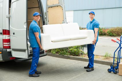 Two Happy Male Workers Putting Furniture And Boxes In Truck